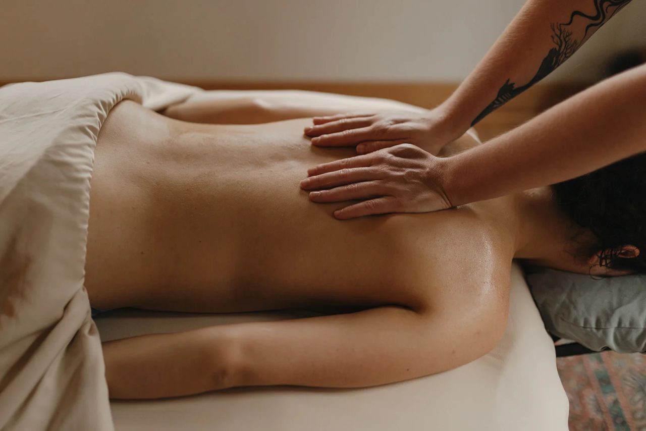 Two hands working the muscles of the upper back, mid-stroke.